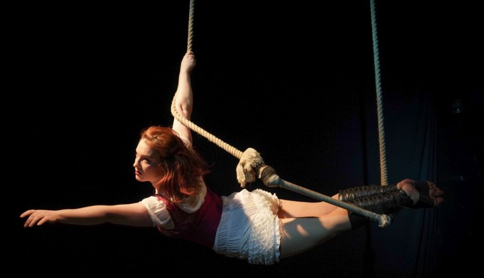 An aerial performer hanging onto a rope