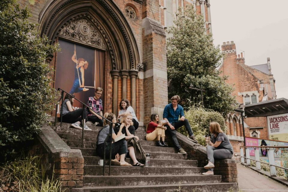 A group of artists sit on the steps of the Jacksons Lane theatre
