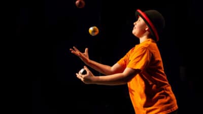 Young performer wearing a bowler hat, juggling