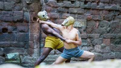 two performers wearing gas masks