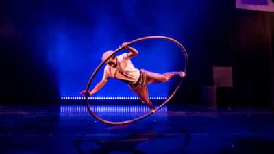 Prince Charming spins around in a cyr wheel while wearing a sequined suit