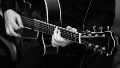 Close up black and white photo of hands playing a guitar