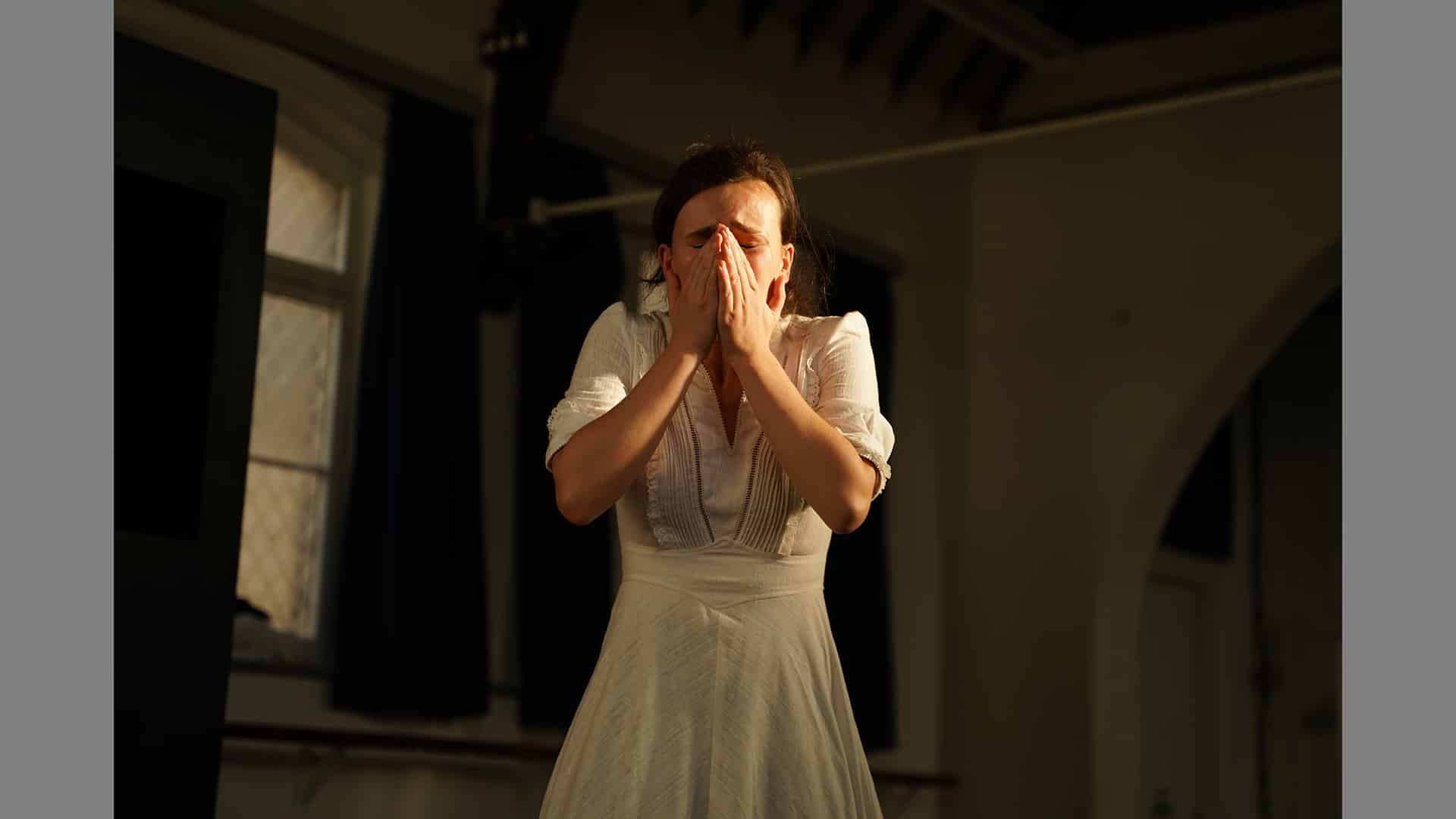 A woman covers her mouth with her hands as she cries