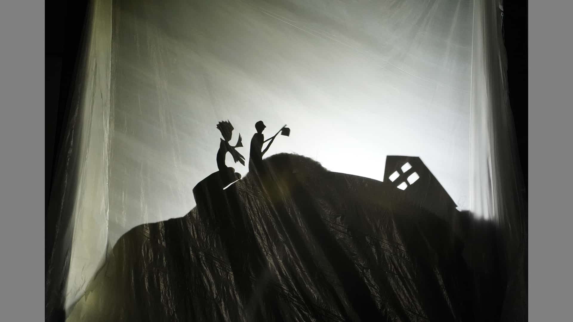 Shadowpuppet scene with two figures climbing a hill towards a building