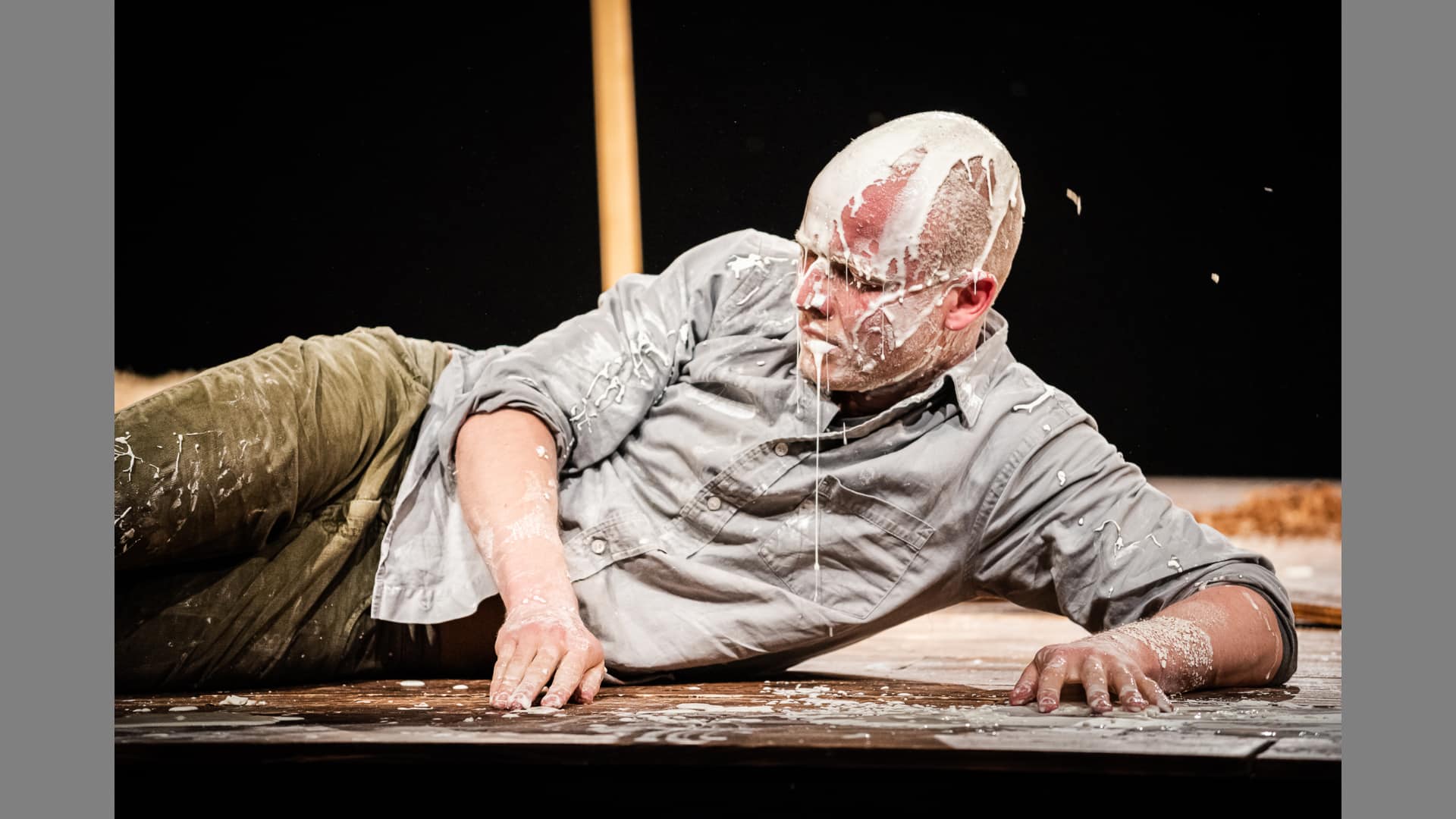 A performer reclines on stage, his face dripping with white glue