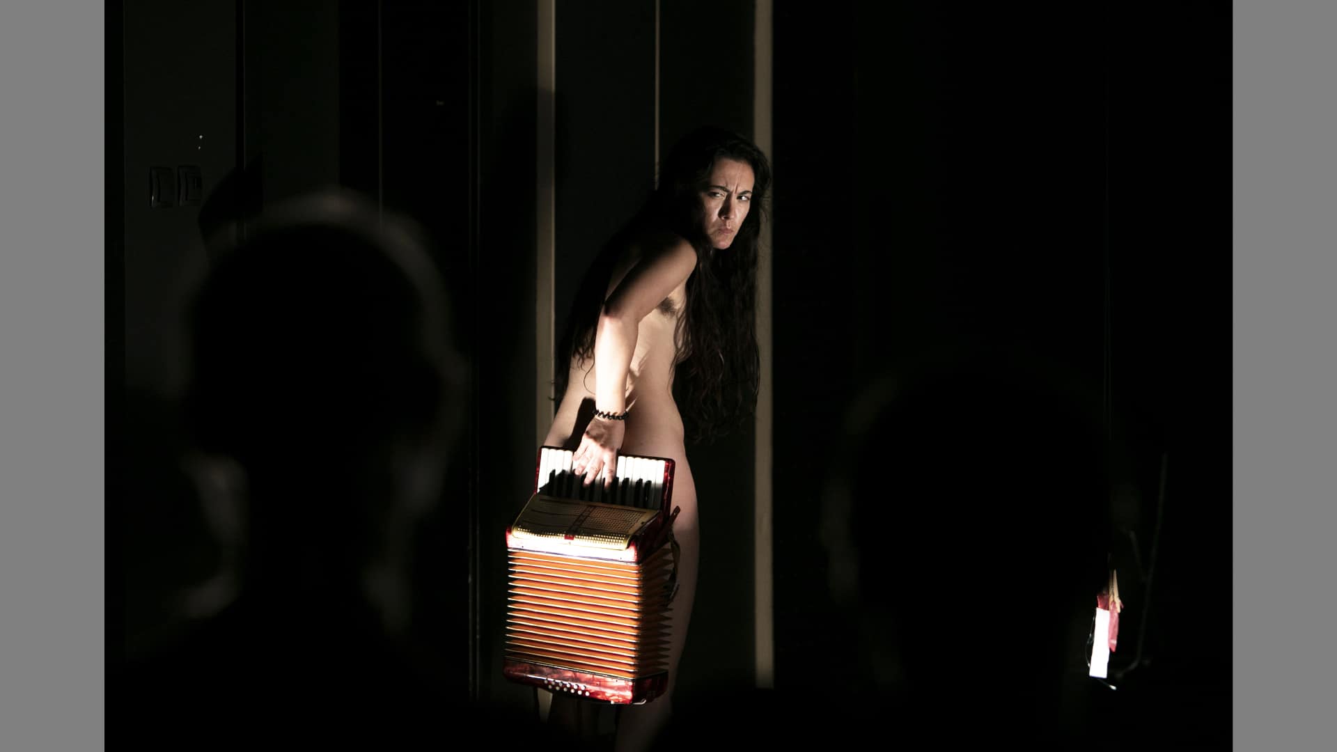 Eloina hides her naked num with an accordian