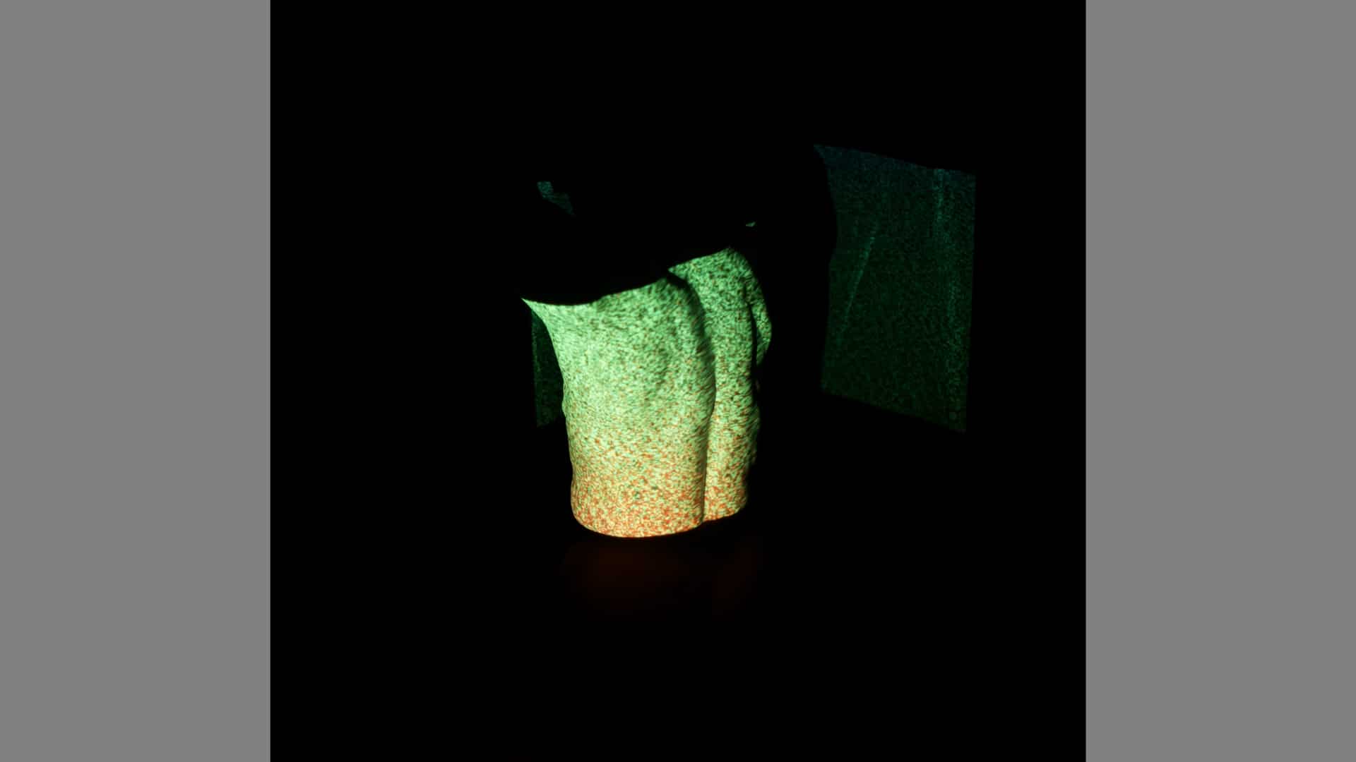 A naked back is lit with green and gold light