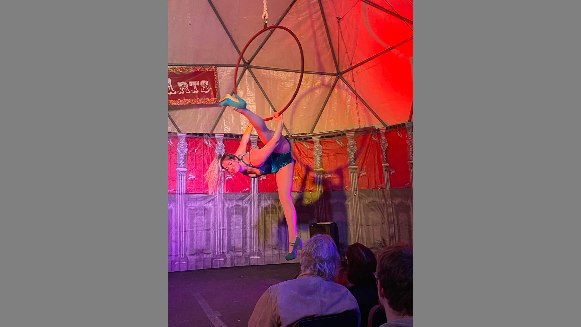An woman does the splits on an aerial ring