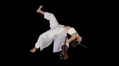 Violinist Sonja Schebeck tumbles backwards in a black void, holding onto her violin