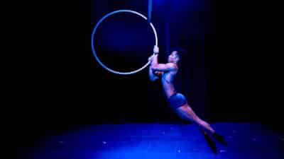 Zaki Musa grips on to the side of an aerial hoop, his skin bathed in blue light
