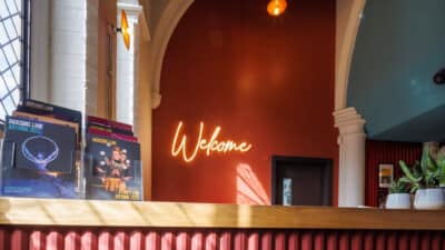 The neon sign saying Welcome glows brightly behind the Welcome Desk in the foyer at Jacksons Lane
