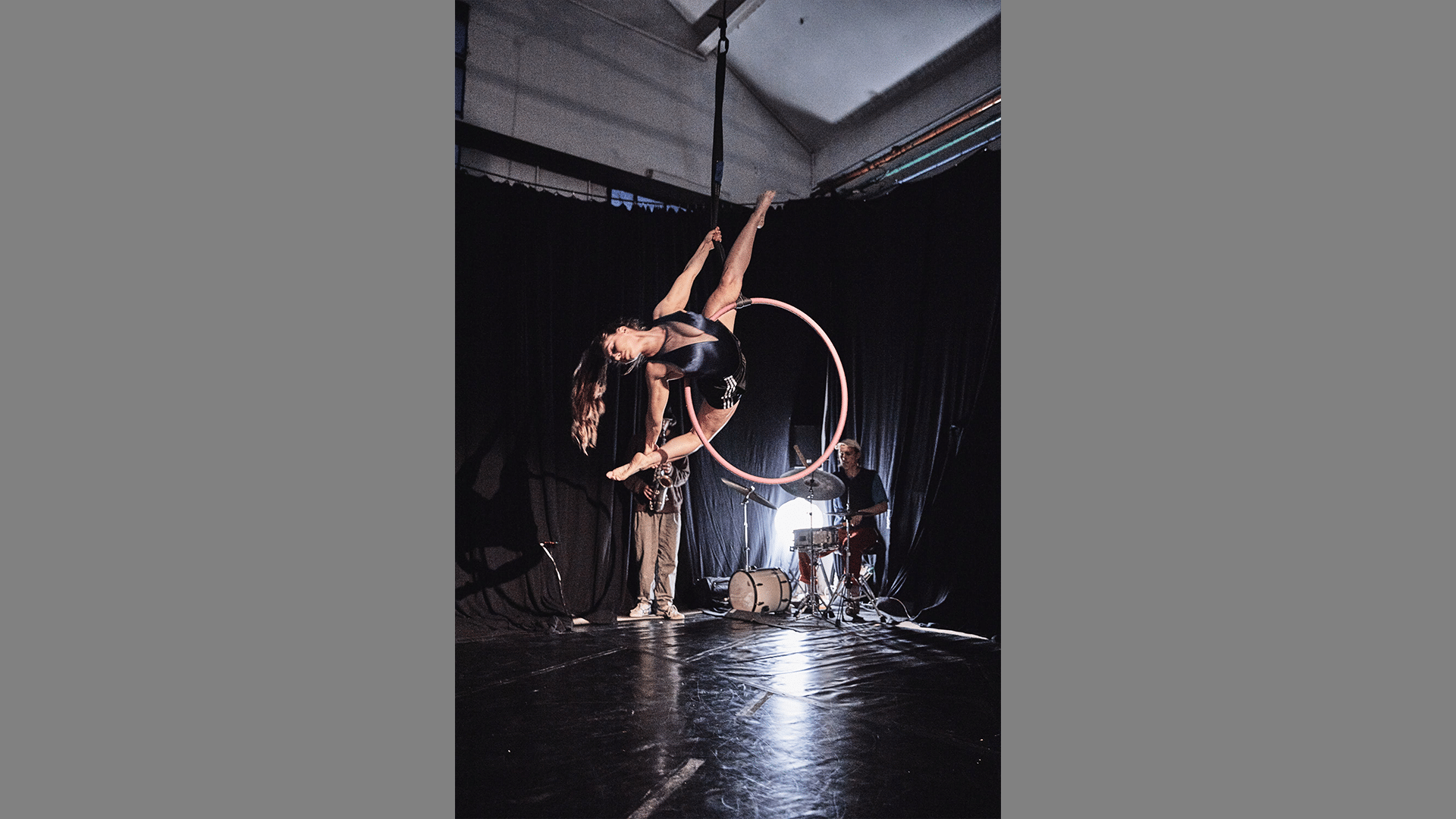 A performer performs a split on an aerial hoop.