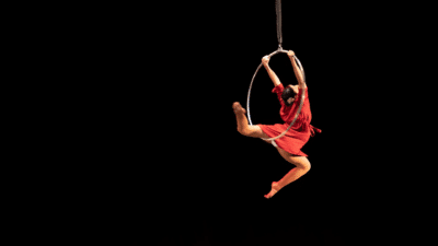 A circus performer performs a backbend move on an aerial hoop.