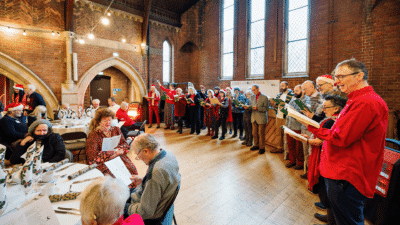 A group of people singing carols in a large hall.